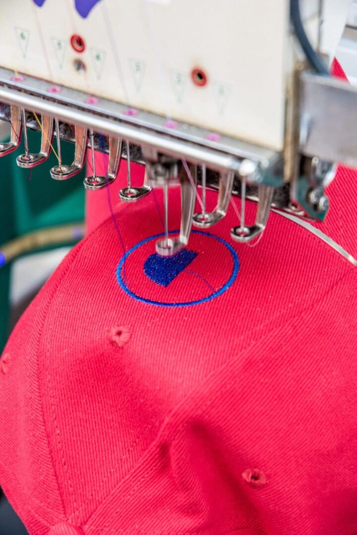 GettyImages-952120098 A red hat being embroidered with blue thread.